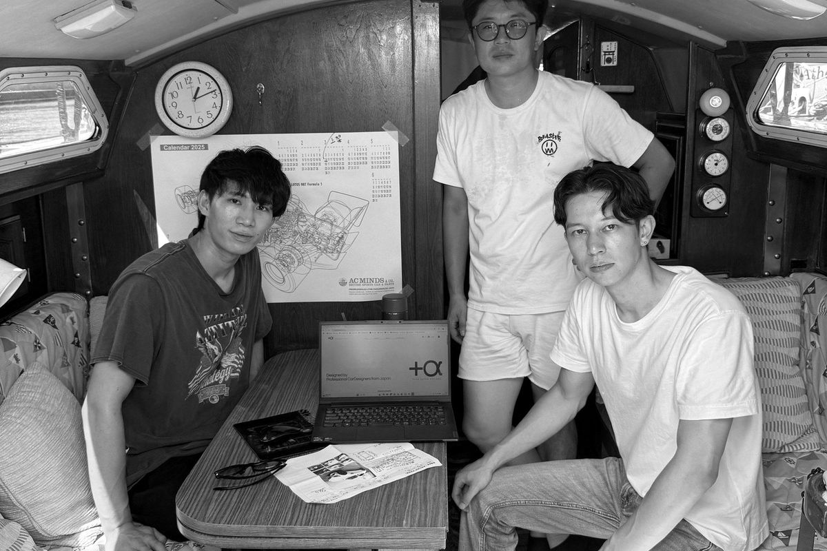 創業メンバーの3人。壁にロータス98Tのカットアウェイ図
